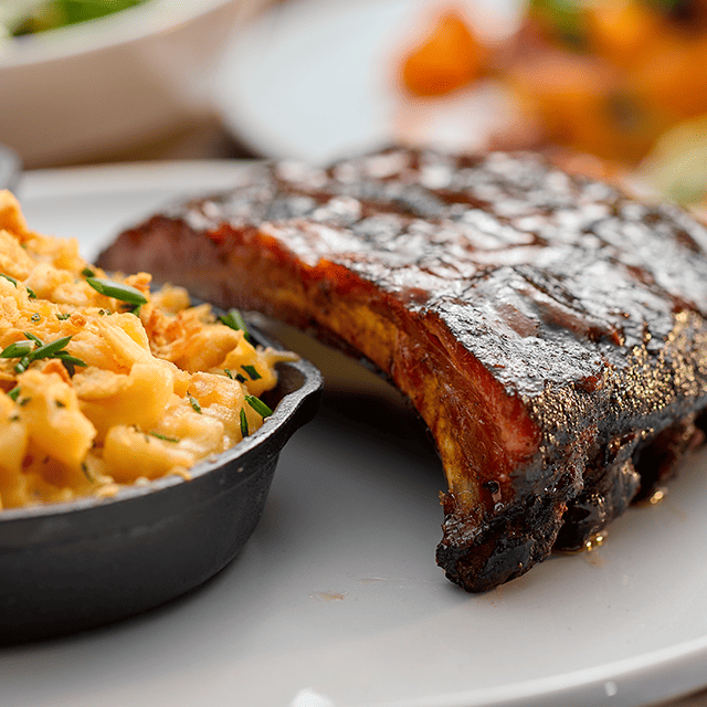 A close-up photo of a half-rack of ribs and a side of mac-and-cheese.
