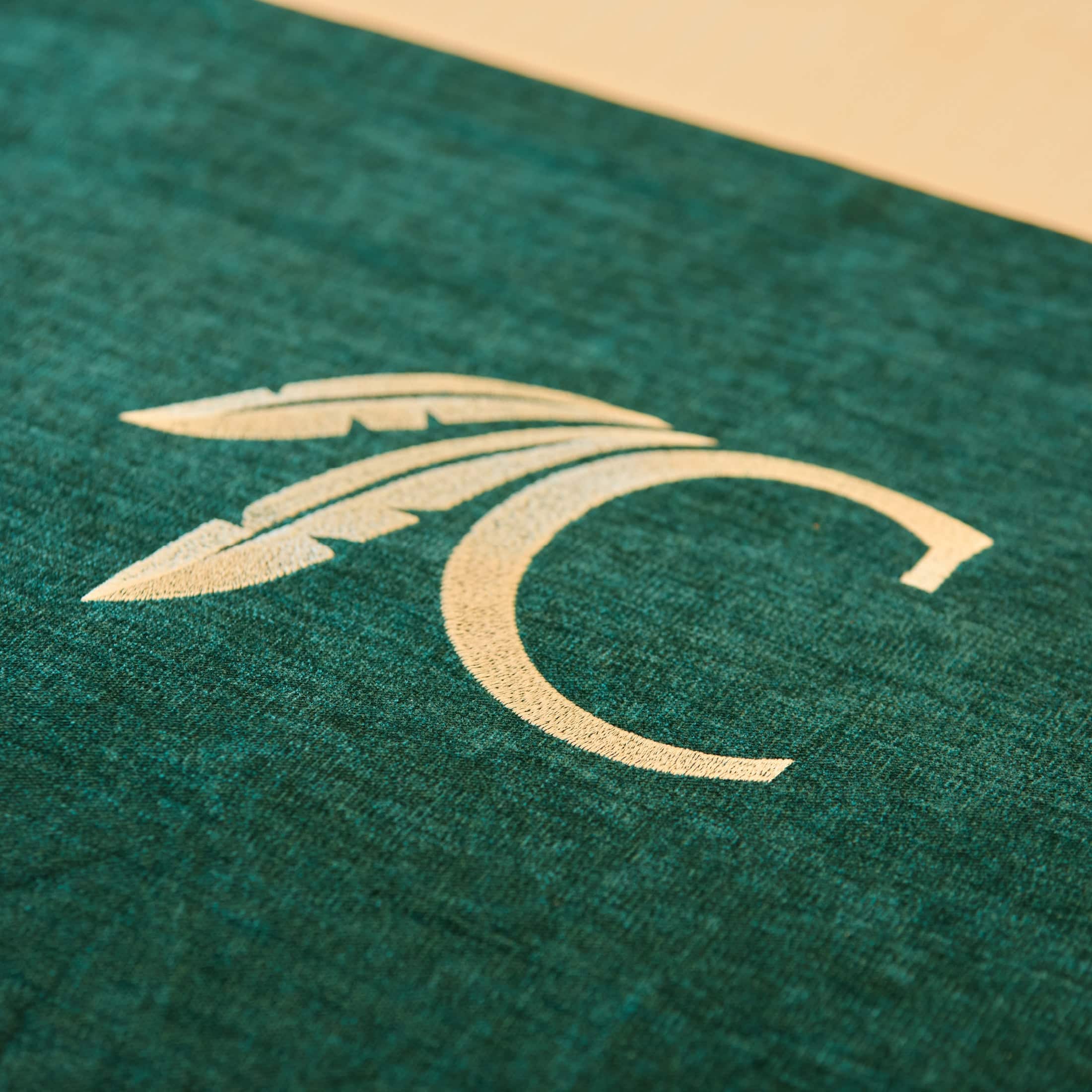 A close-up of the Choctaw "C" logo on a green bedspread.