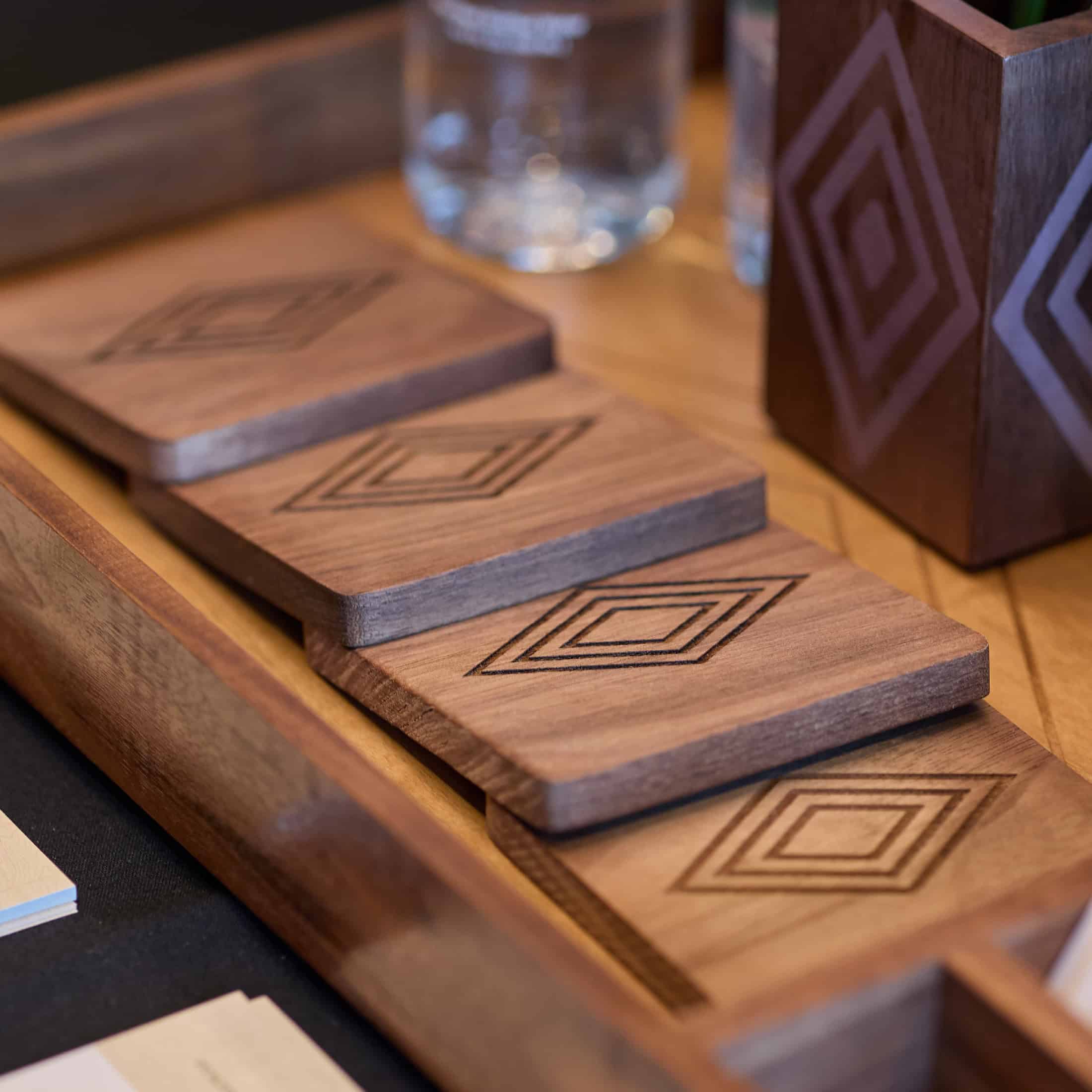 Wooden coasters with diamonds engraved in the center are stacked on a table