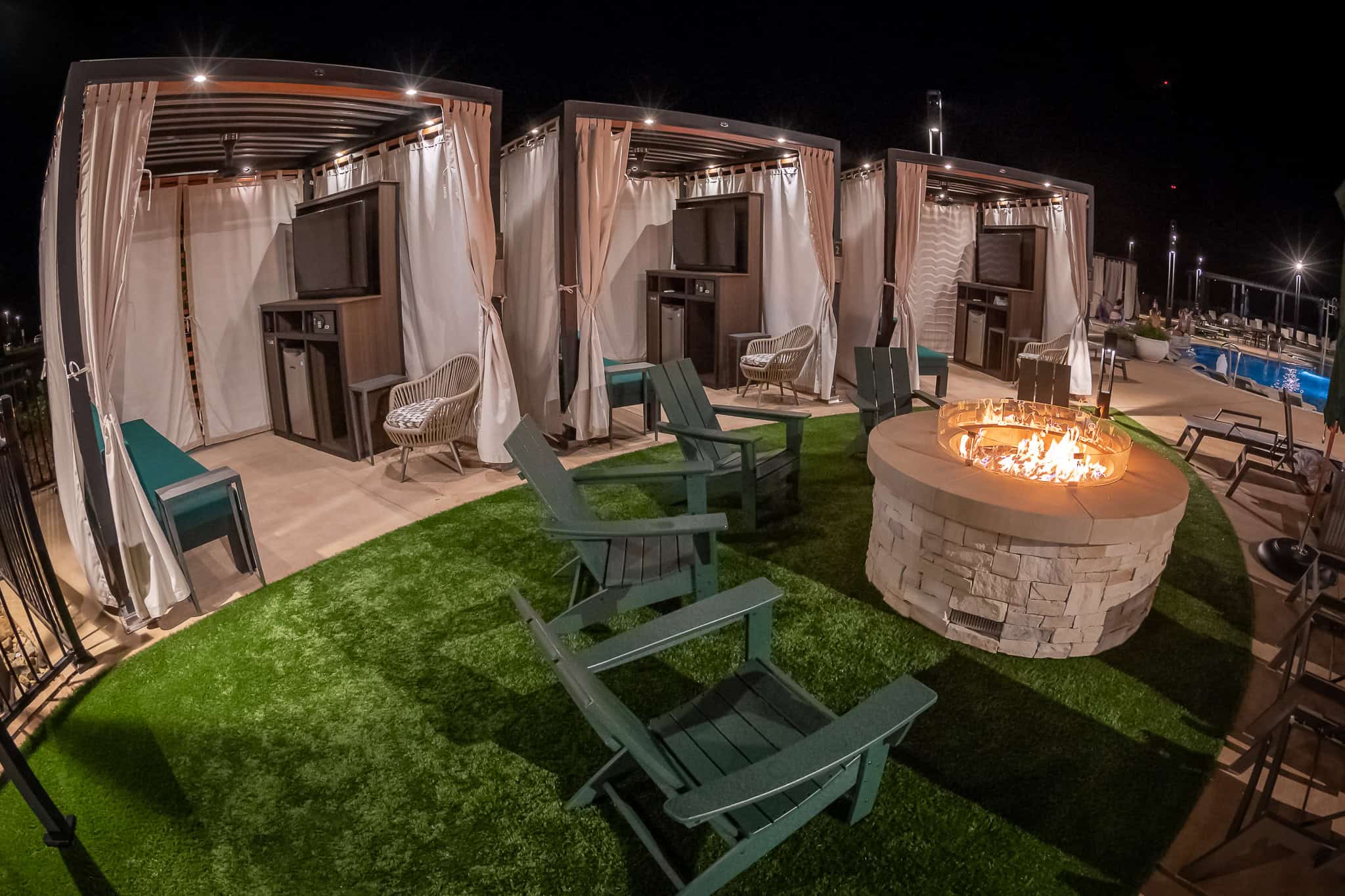 three cabanas in a row behind a fire pit.