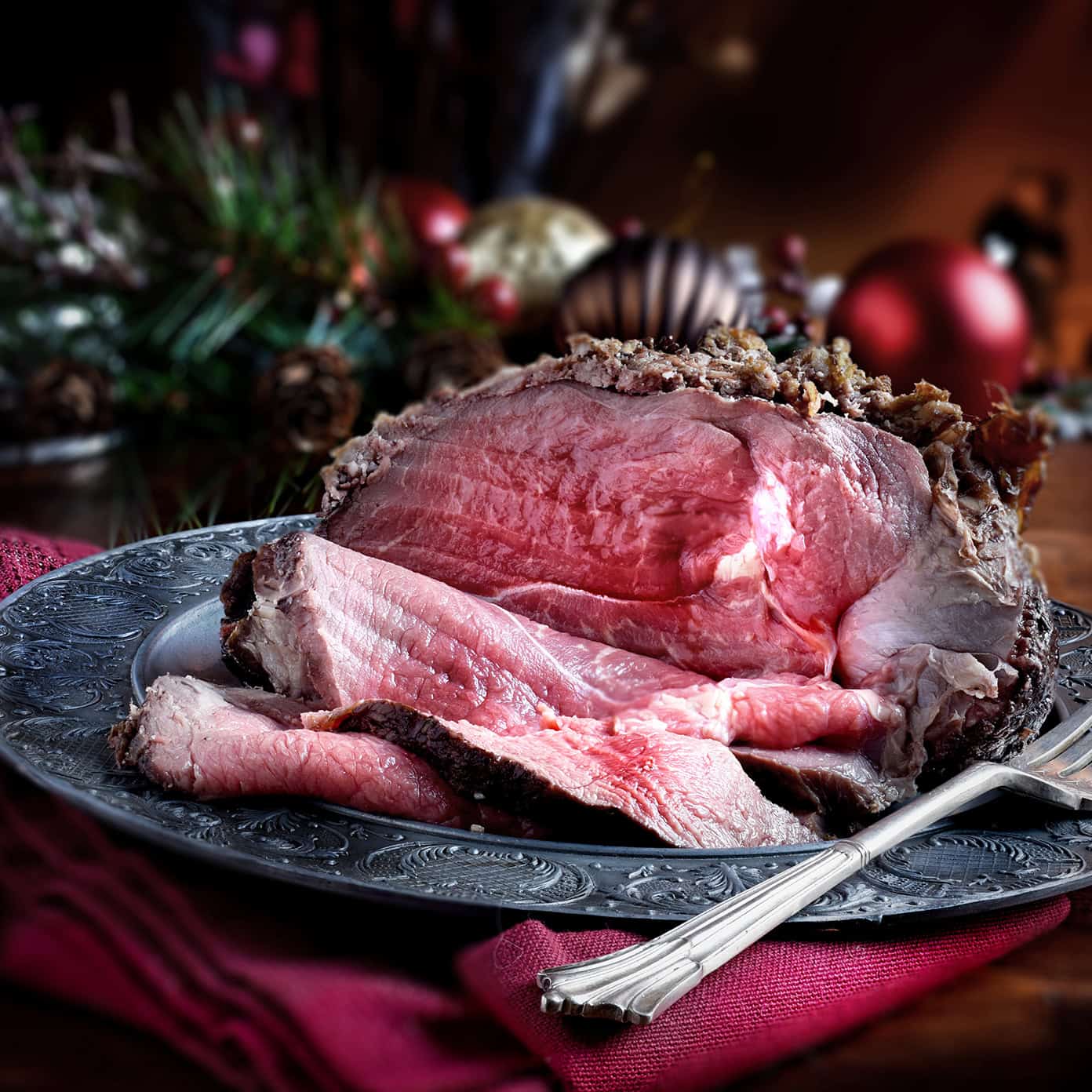 Rare cooked sliced roast beef joint against a rustic Christmas background for the Christmas Buffet at Tuklo Grill at Choctaw Landing